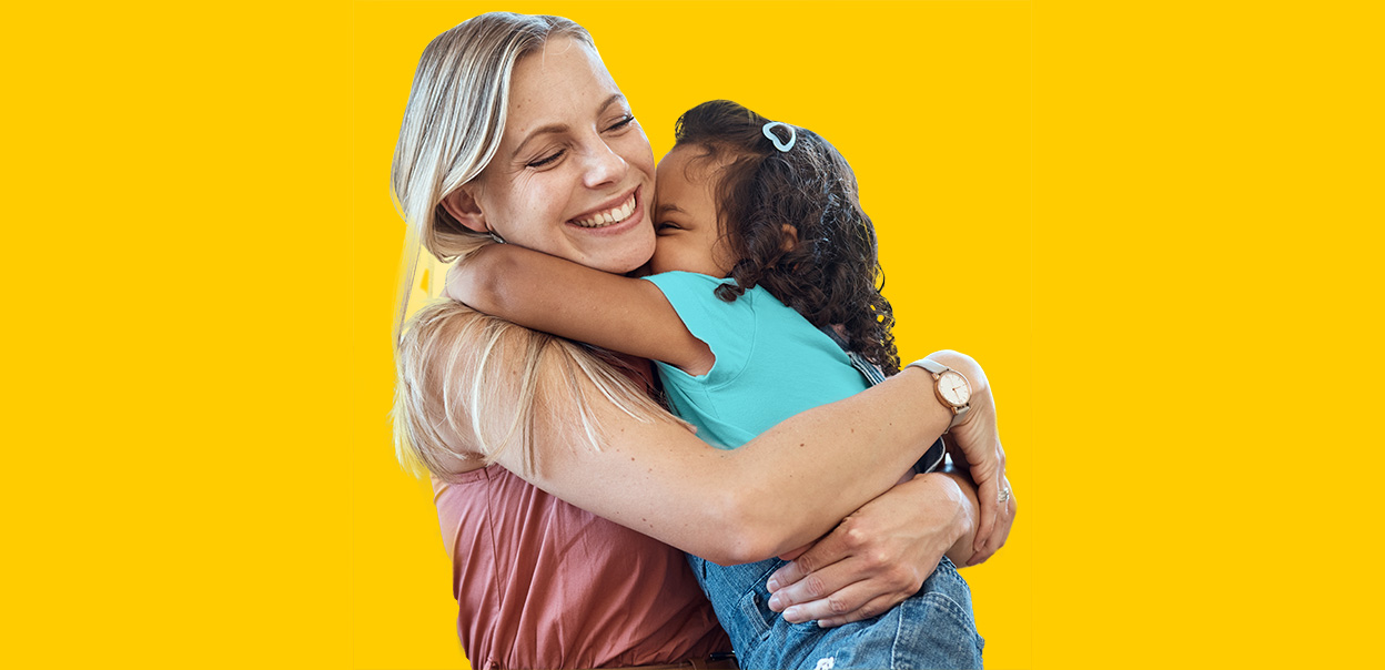 An adult and child sharing a hug at home.